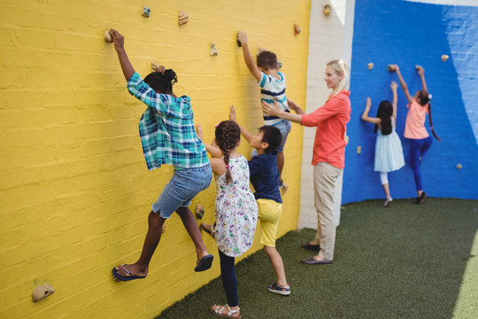 培训师协助孩子在学校爬墙