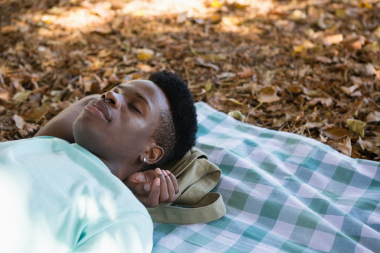 躺在公园里的野餐毯上的男人