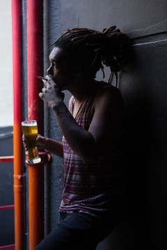 在酒吧门口喝啤酒时抽烟的男人