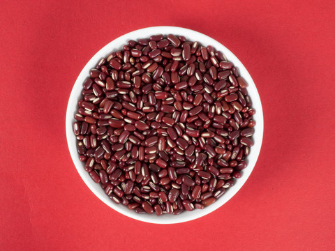 红色背景里的瓷盘上的赤小豆