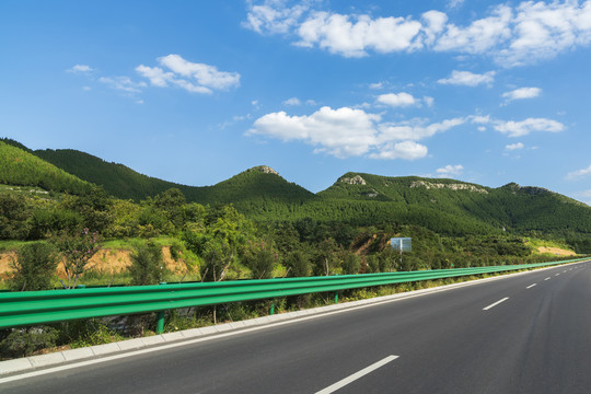 青山蓝天白云背景的沥青公路