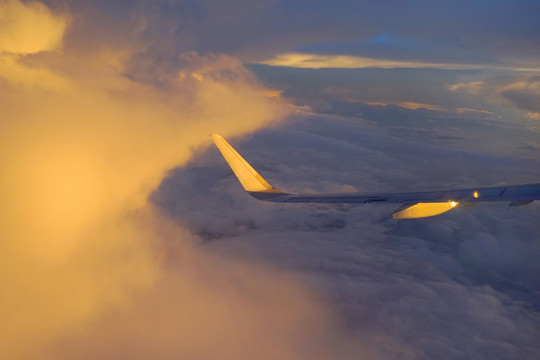 在傍晚云层中飞行的飞机机翼