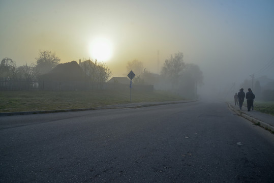 早晨雾中村庄公路的行人