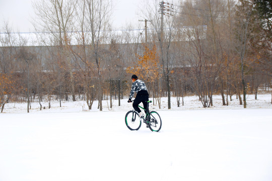 冬天雪地里骑单车自行车的小男孩