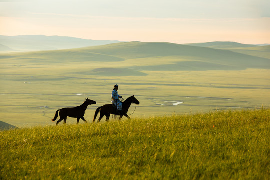 清晨草原上骑马的蒙古族男人