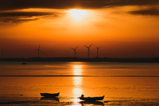 日出时海边的小船和风车