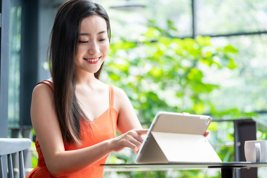 年轻女子看咖啡店使用平板电脑