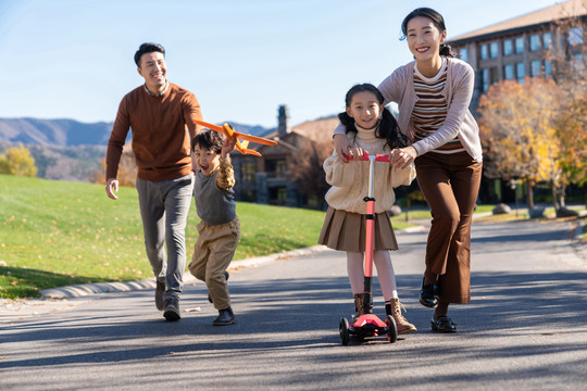 年轻夫妻带着孩子们在玩滑板车