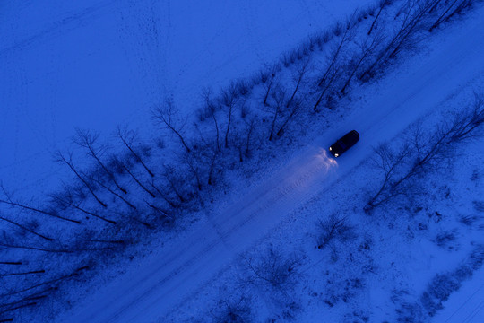 一辆越野车在雪原夜色道路上行驶