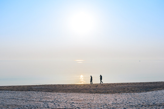 冬天清晨海边散步的两个人