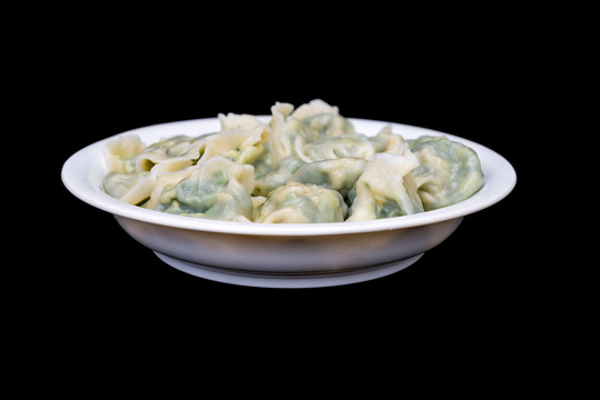 黑背景白色盘子中煮熟的水饺