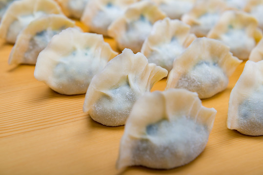 黄色木纹板上摆放的韭菜鸡蛋馅饺