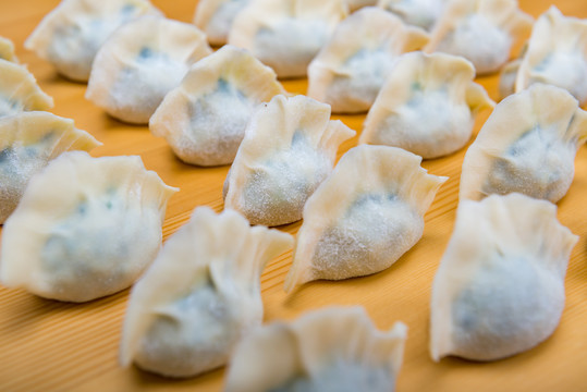 黄色木纹板上摆放的韭菜鸡蛋馅饺