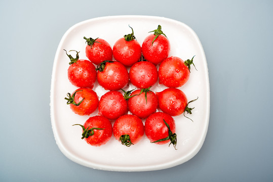 白背景下摆放在白盘子里的小番茄