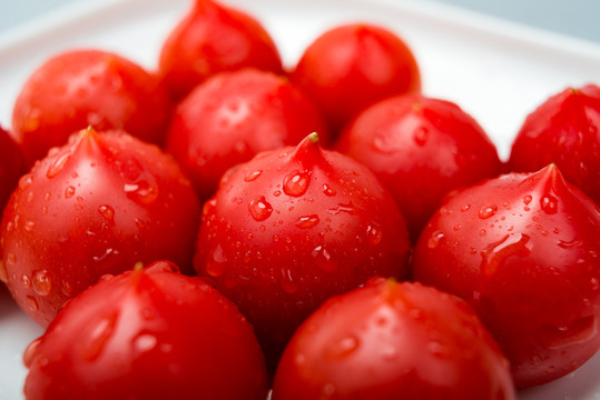 白背景下摆放在白盘子里的小番茄