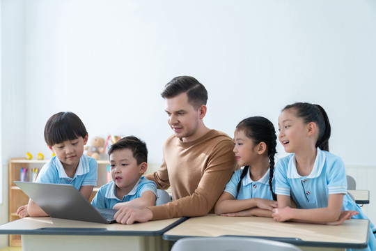 老师在课堂上辅导小学生用电脑