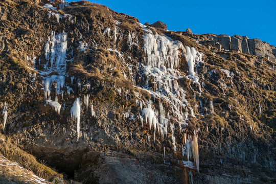 阳光下冬季悬崖石壁上的冰晶冰锥