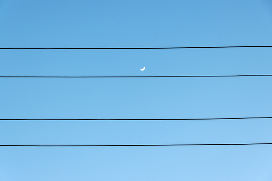 蓝天下有供电线路前景的初升晓月
