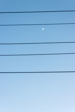 蓝天下有供电线前景的初升月亮