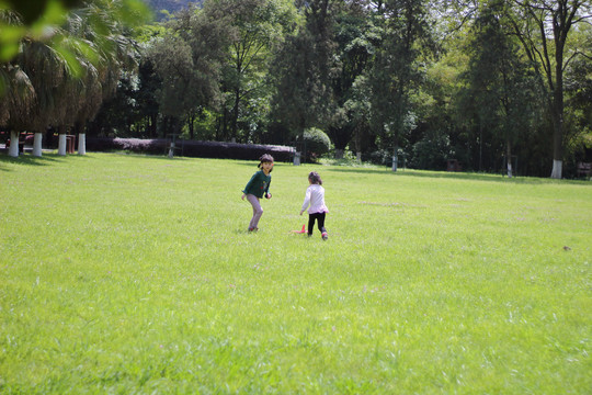 在草地上一玩的两个小女孩
