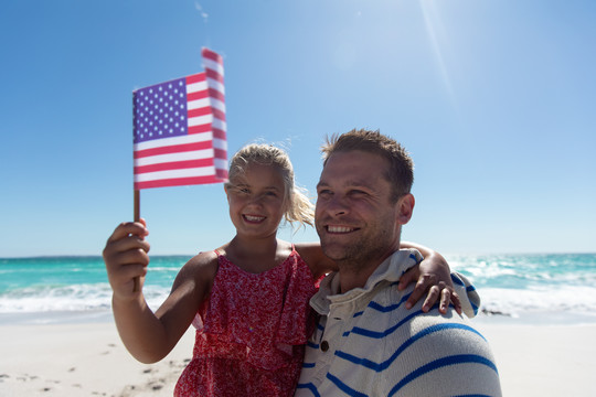 女孩和父亲一起举起美国国旗