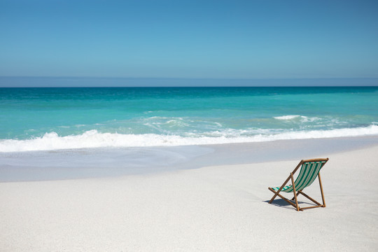 坐在沙滩上的空躺椅
