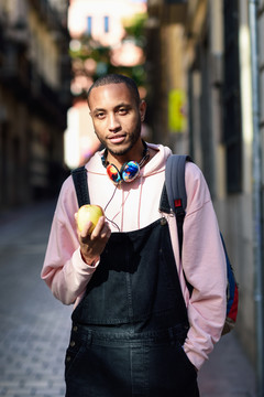 年轻的黑人在街上吃苹果