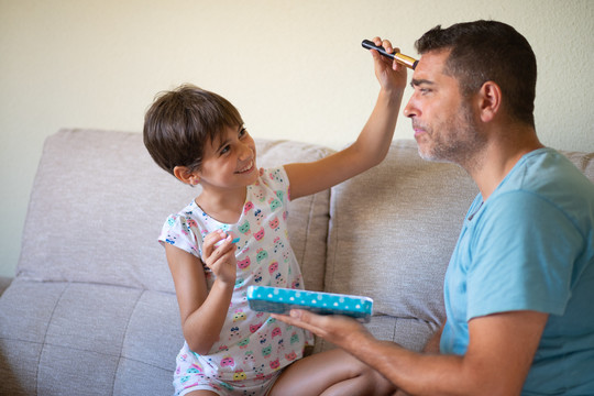 可爱的小女儿在给她父亲化妆