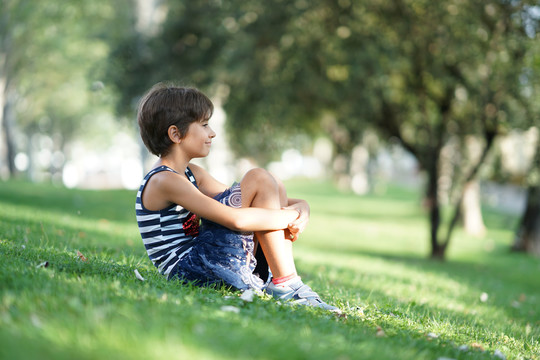 八岁的小女孩坐在户外的草地上