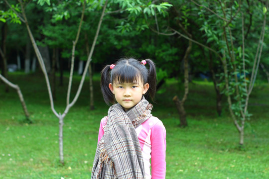 户外草地上围着大围巾的小女孩