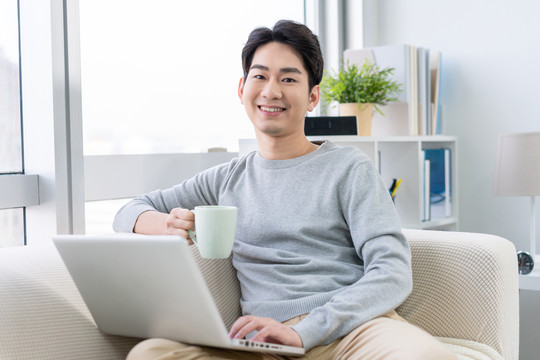 年轻男子在沙发上使用笔记本电脑