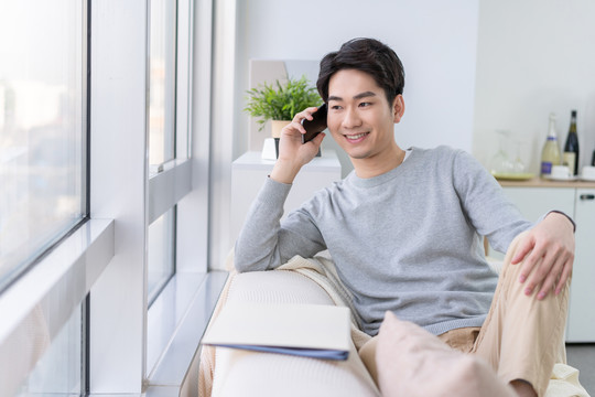 年轻男子坐在沙发上打电话