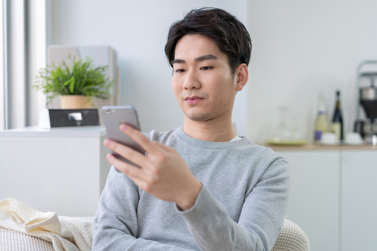 年轻男子坐在沙发上使用手机