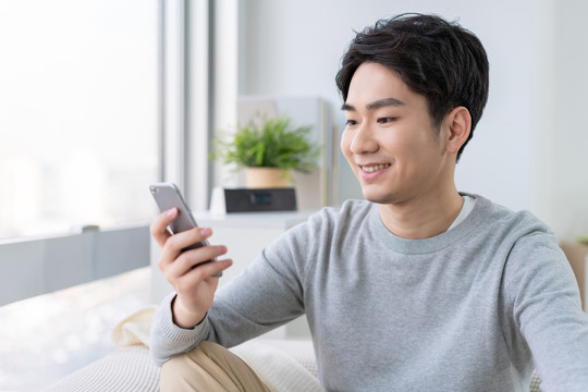 年轻男子坐在沙发上使用手机