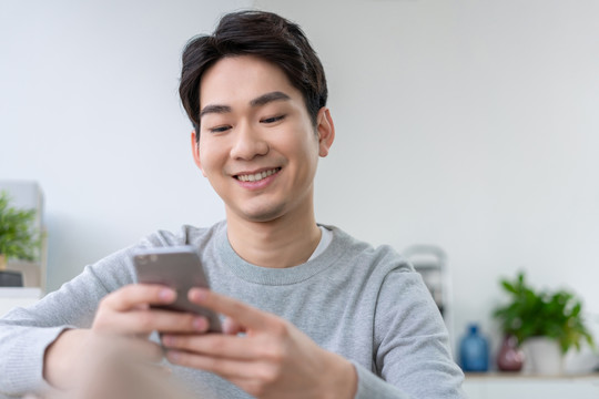年轻男子坐在沙发上使用手机