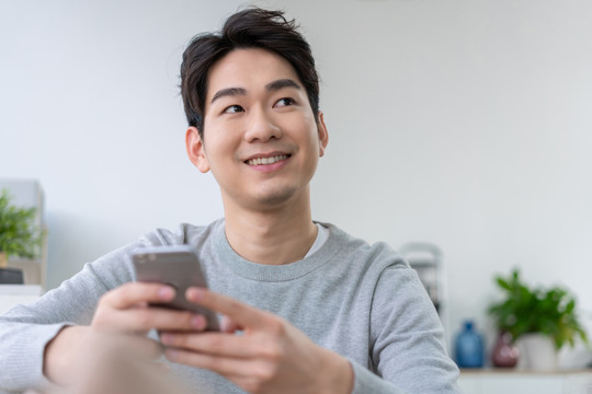 年轻男子坐在沙发上使用手机