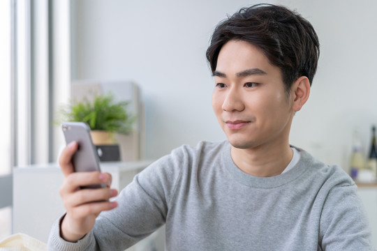 年轻男子坐在沙发上使用手机