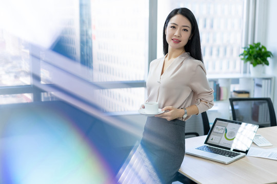 年轻商务女士在办公室喝咖啡