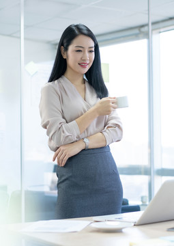 年轻商务女士在办公室喝咖啡