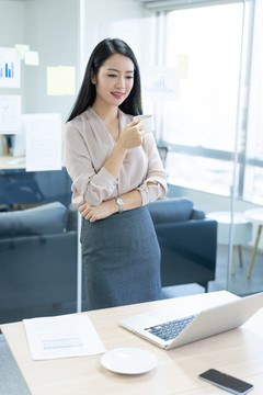 年轻商务女士在办公室喝咖啡