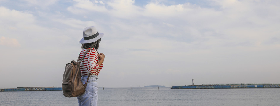 背着背包在海边欣赏风景的女人背