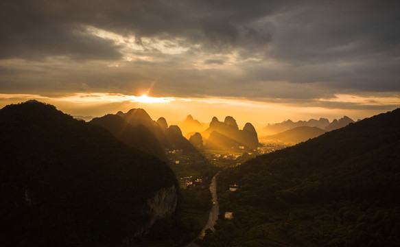 夕阳的金光洒在群山间的公路上