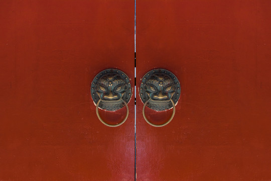 中式红色木门上的兽头叩门环和铜