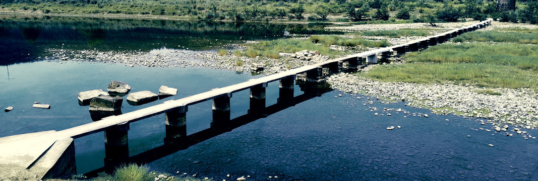 清澈河水边的长长的老桥