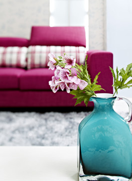 玫瑰色沙发前插着粉红桃蓝色花瓶