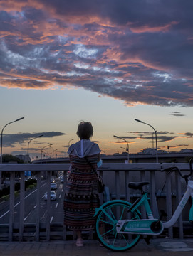 一位行人在城市天桥上观看夕阳