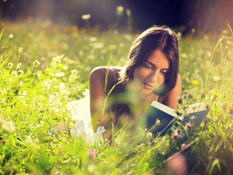 躺在草地上看书的年轻女子