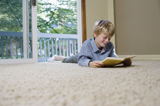 躺在地毯上看书的男孩