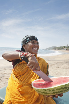 在海滩切西瓜的印度女性