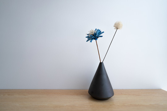 木质书桌上的黑色复古花瓶和假花